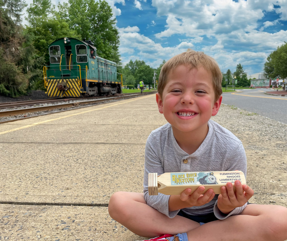 boy sitting on train platform in front of diesel train