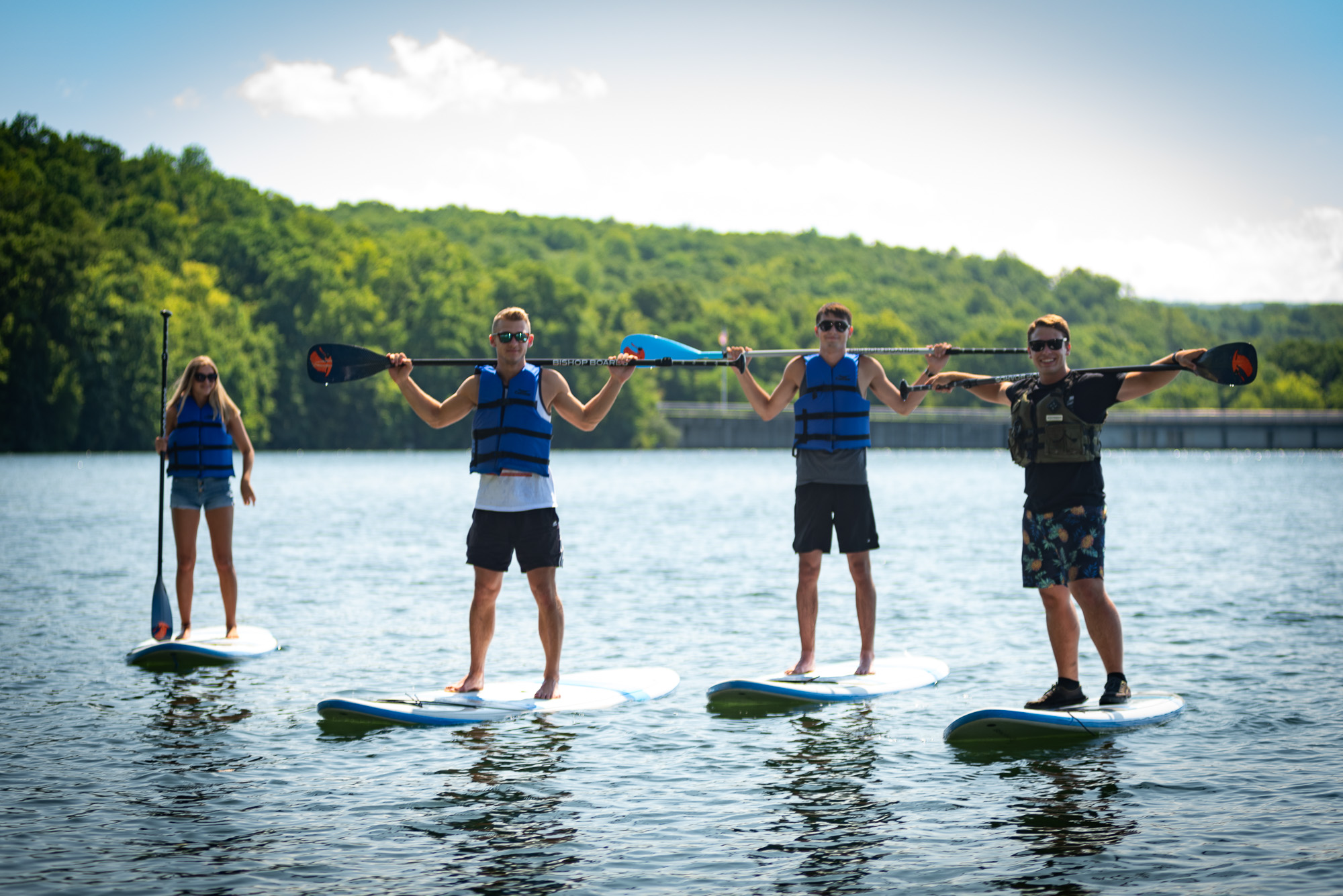 Four people standing on paddleboards on a lake