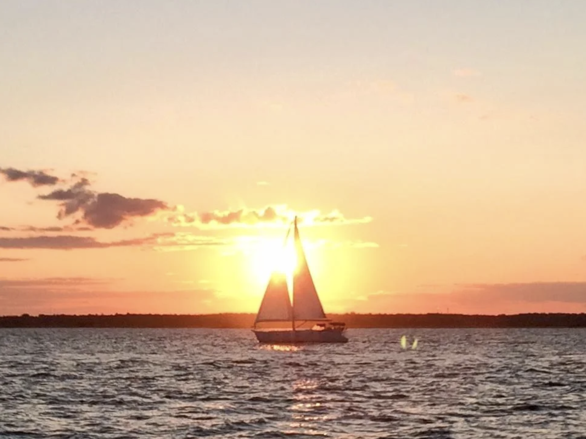 boat sails through sunset