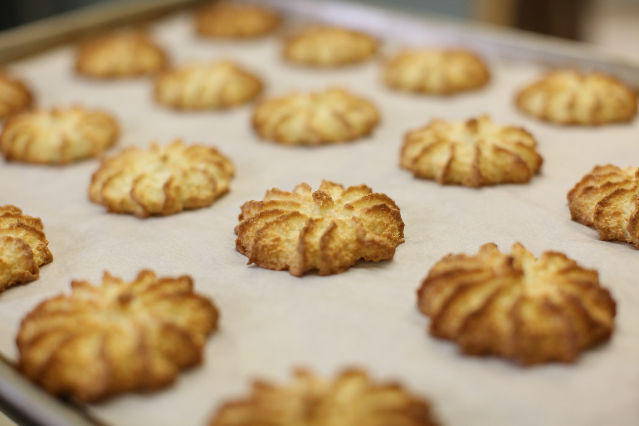 sheet of coconut macarons out of oven cooling