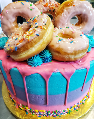 colorful round cake with sprinkled & frosted donuts stacked on top