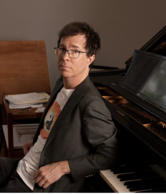 Ben Folds sitting against piano