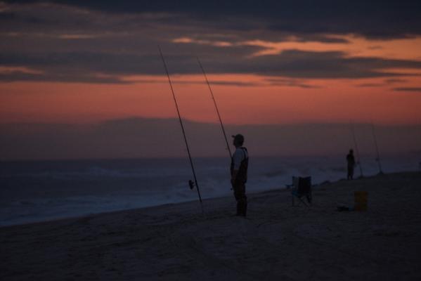 anglers casting for fish on the beach in sunset
