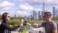 Image of man and woman sharing a wine toast in front of a city skyline