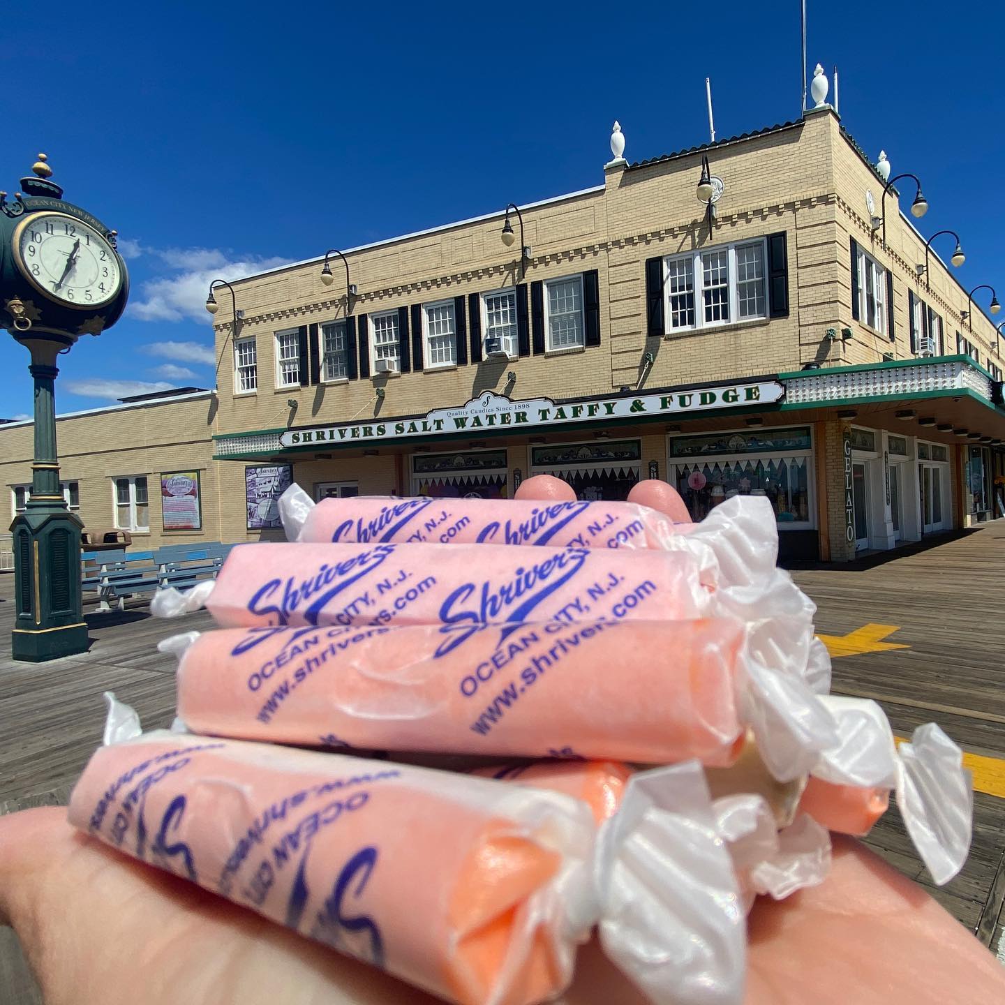 salt water taffy in palm of hand in front of building on the boardwalk